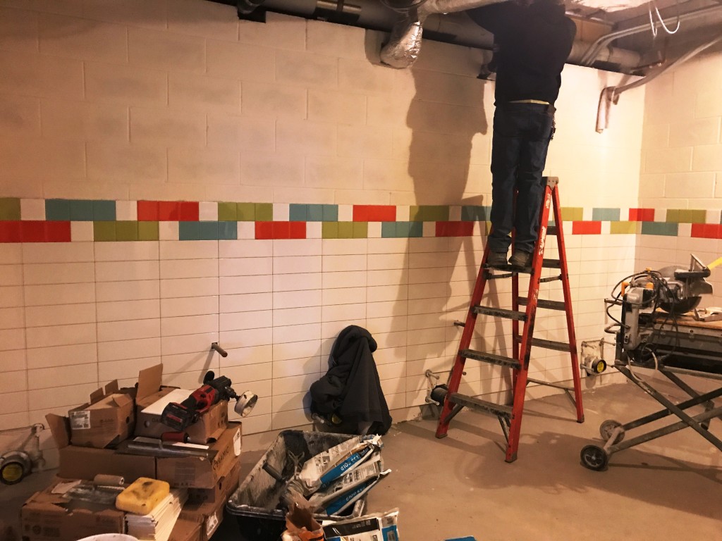 In the locker rooms, ceramic tile on both the floors and the walls is being installed. The lockers themselves are on site anxiously await their installation.